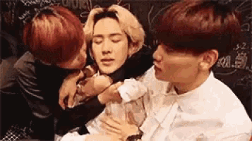 a group of young men are hugging each other and one of them is kissing another man on the cheek .