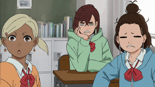 three anime girls are sitting at desks in a classroom with one girl making a funny face