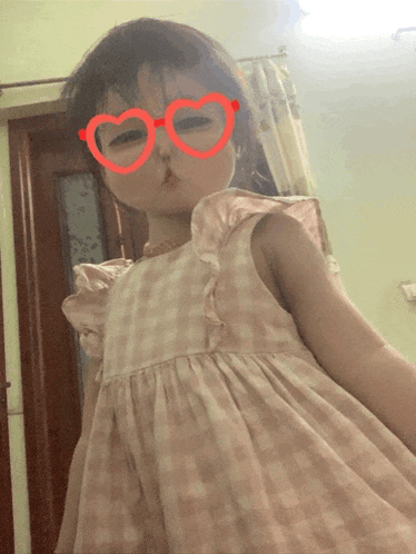 a little girl wearing heart shaped glasses is making a face