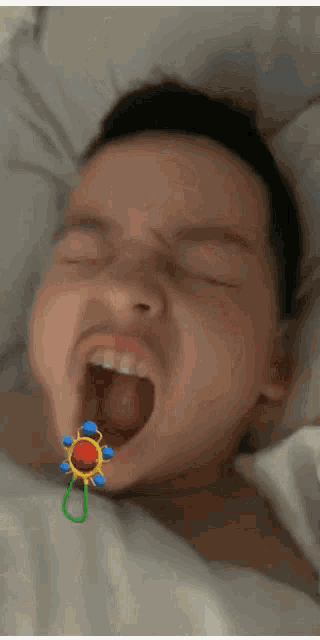 a baby with a pacifier in his mouth yawning
