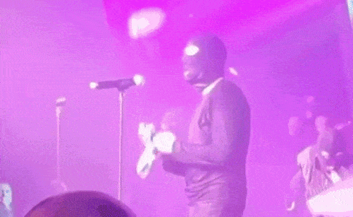 a man in a mask is singing into a microphone on a stage .