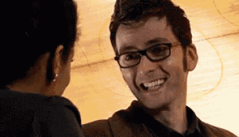 a man with glasses is smiling at a woman