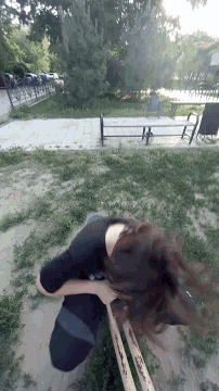 a woman in a black shirt is walking down a path in a park