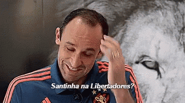 a man wearing a shirt that says santinha na libertadores is smiling .