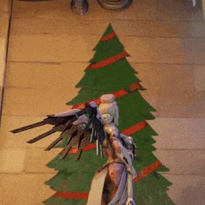 a christmas tree with red ribbons is behind a statue of an angel