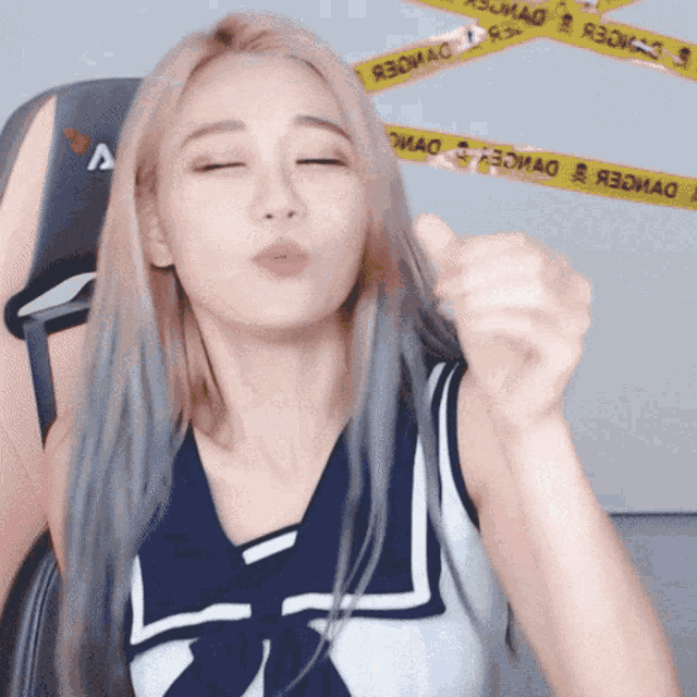 a woman blowing a kiss in front of a yellow tape that says ' я3оиаo ' on it