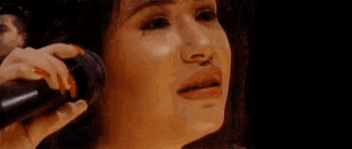 a close up of a woman holding a microphone in her hand and smiling .