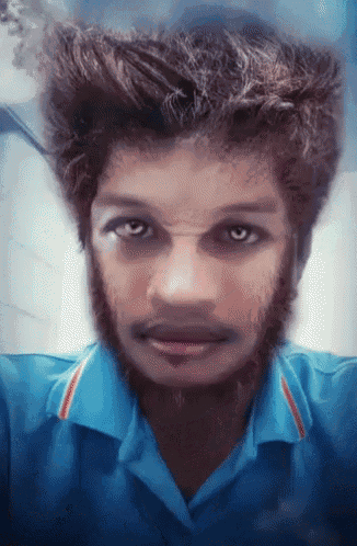 a young man in a blue shirt has a beard