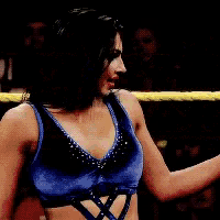 a woman in blue shorts is standing in a wrestling ring with another woman