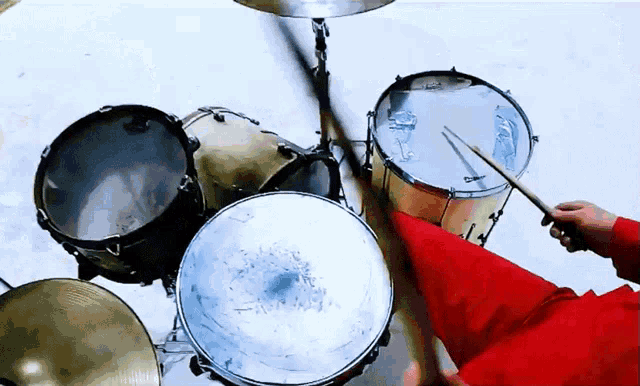 a person in a red jacket is playing drums