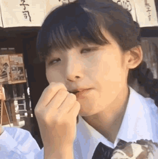 a girl in a white shirt and tie is eating a piece of food .