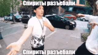 two men are standing on a sidewalk with their arms outstretched in front of a parking lot ..