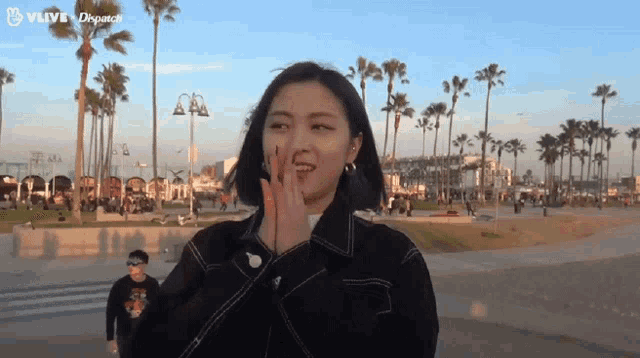 a woman covering her nose with her hand in front of palm trees ..
