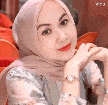 a woman wearing a hijab and a watch is posing for a picture .