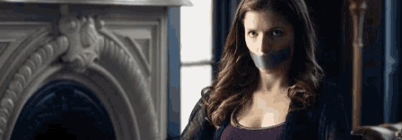 a woman with tape on her mouth is sitting in front of a fireplace .