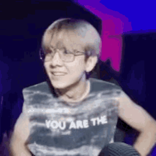 a young man wearing glasses and a sleeveless shirt that says `` you are the '' is smiling .