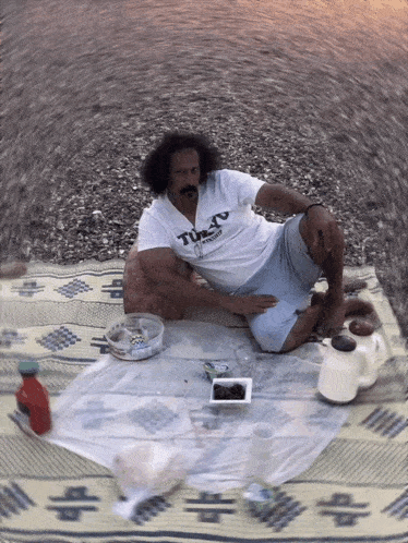 a man is sitting on a blanket wearing a t-shirt that says tokyo