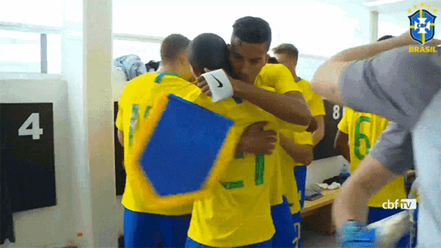 a group of soccer players are hugging in a locker room with the number 4 on the wall behind them