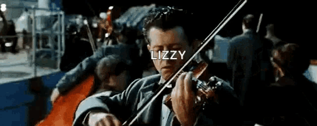 a man is playing a violin in front of a crowd while standing on a boat .