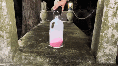 a person pouring liquid into a plastic bottle with a handle