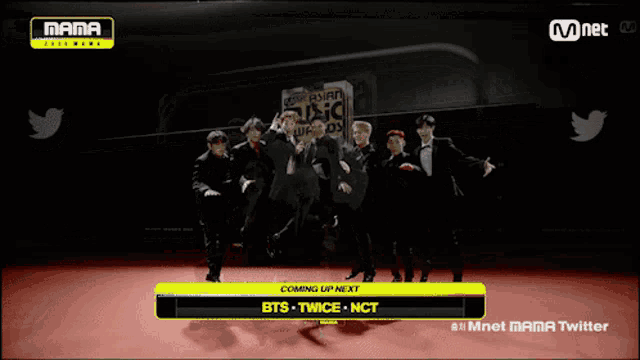 a group of men are dancing in front of a sign that says mnet