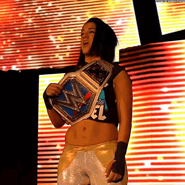 a woman is holding a wrestling championship belt on a stage