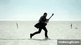 a man is flying through the air while holding a guitar in the ocean .