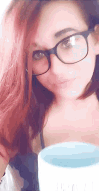 a woman wearing glasses is holding a blue cup