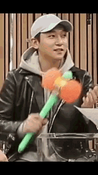 a man wearing a baseball cap and a leather jacket is holding a green and orange toy .