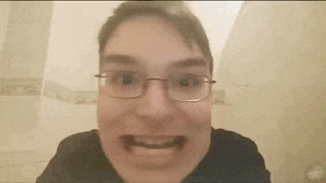 a man wearing glasses and a black shirt is making a funny face in a bathroom .