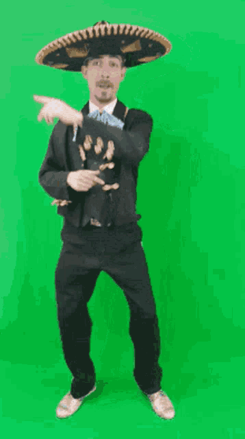 a man wearing a sombrero and a suit is dancing on a green screen