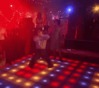a group of people are dancing on a colorful dance floor