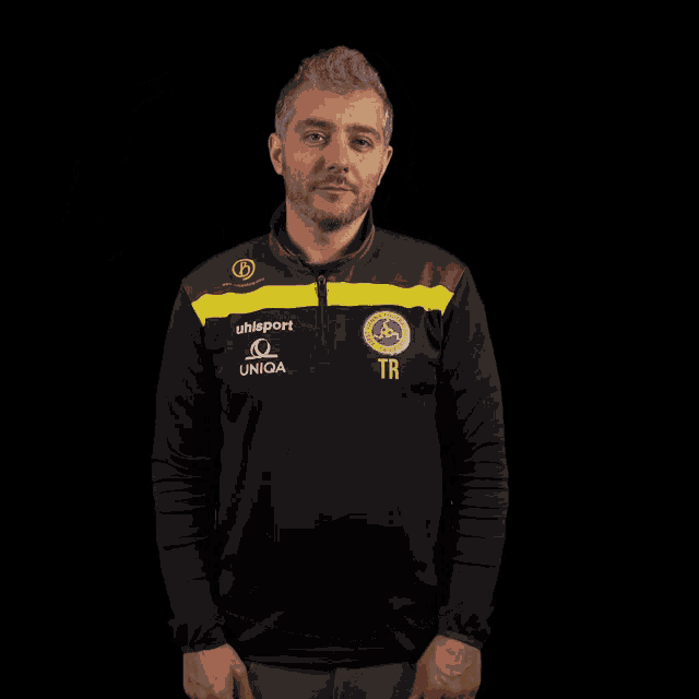 a man wearing a black and yellow shirt that says uhlsport and uniqa