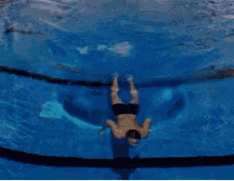 a man is swimming in a swimming pool with a black rope