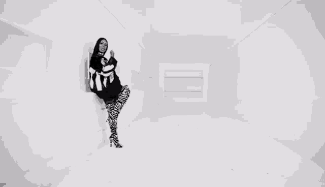 a woman in zebra print pants is standing in a white room