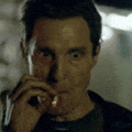 a man is smoking a cigarette in a dark room and making a funny face .