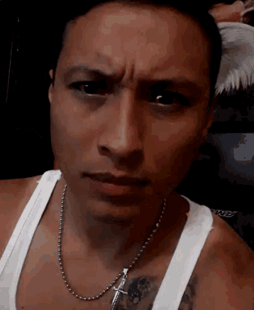 a man wearing a white tank top has a tattoo on his chest
