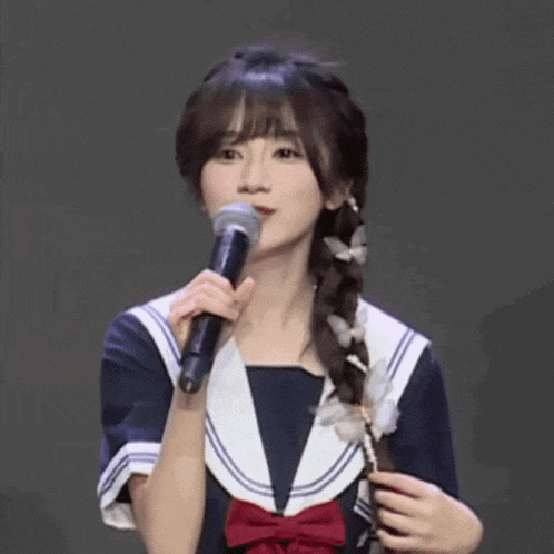 a girl in a sailor outfit is singing into a microphone .