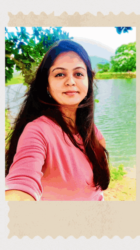 a woman in a pink shirt takes a selfie in front of a lake