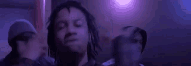 a group of young men are standing next to each other in a room with purple lights .