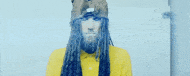 a man with long hair and a beard wearing a yellow jacket and a hat .