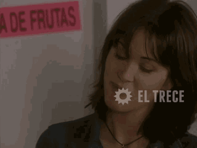 a woman is standing in front of a sign that says a de frutas
