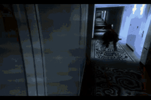 a person is walking down a dark hallway with a blue light behind them
