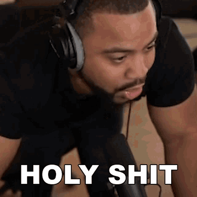 a man wearing headphones is kneeling in front of a microphone and saying holy shit