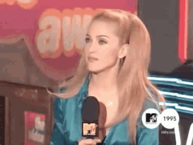 a woman is holding a microphone in front of a mtv logo