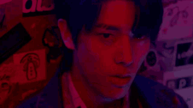 a close up of a man 's face in a dark room with red lights behind him .