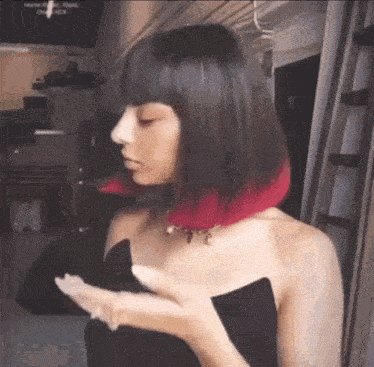 a woman with red hair is wearing a black dress .