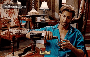 a man is sitting in a chair pouring wine into a glass .