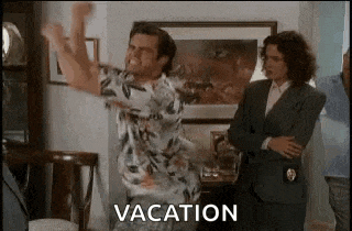 a man in a hawaiian shirt is jumping in the air while a woman stands behind him .