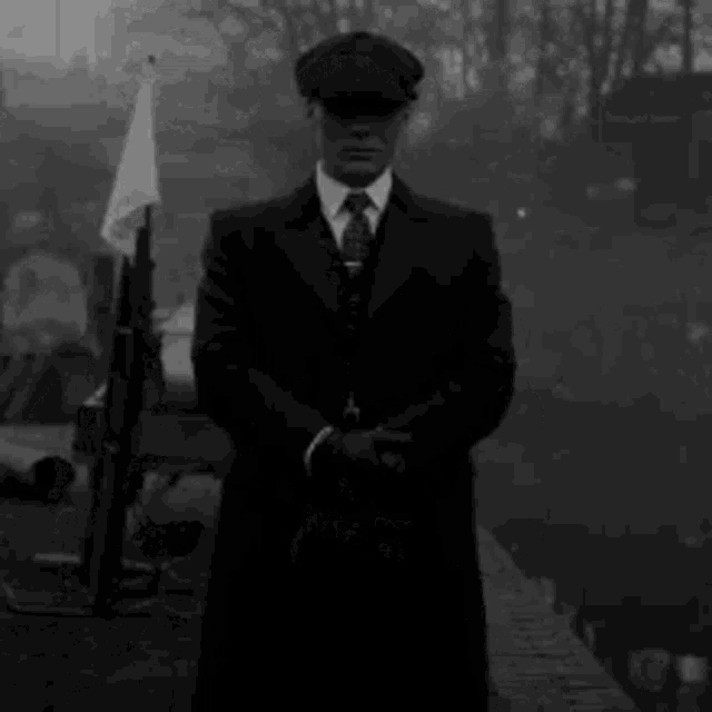 a man in a suit and hat is standing in the fog .